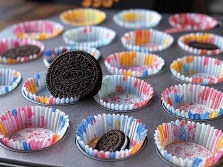A muffin tin with cupcake liners, each with an Oreo cookie at the bottom, ready for batter.