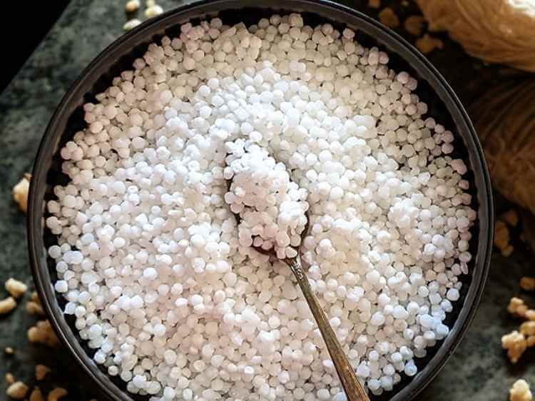 Close-up of white sago pearls soaking in a clear glass bowl of water, ready for making kheer