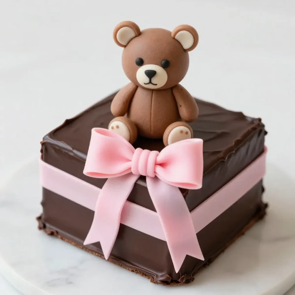 A square chocolate cake decorated like a gift with a fondant teddy bear and a pink buttercream ribbon for Teddy Day.